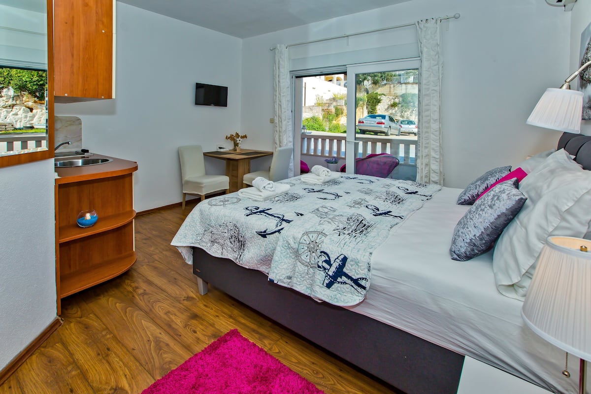 Une chambre à coucher comprenant un lit, un bureau, une chaise, une petite table et une fenêtre donnant sur l’extérieur.