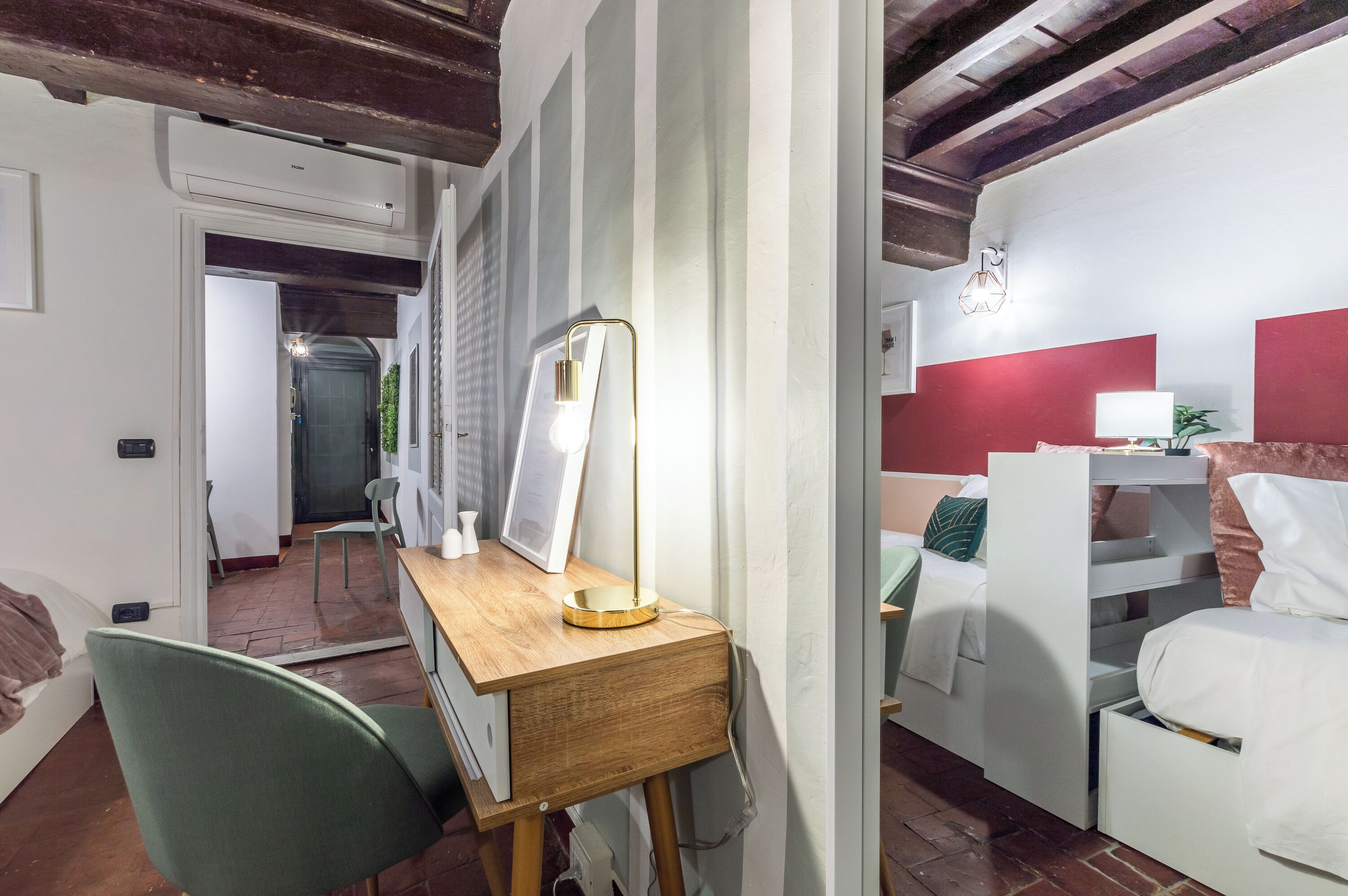 Ein Zimmer mit Schreibtisch, Stuhl, Bett und einer roten Akzentwand.