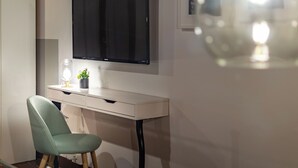 Ein moderner Schreibtisch mit Flachbildschirm, kleiner Topfpflanze und einer Schreibtischlampe.