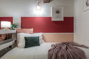 A bedroom with a bed, a bedside table, a lamp, a wall art piece, and a red and white color scheme. - Wine Apartments Florence Ciliegiolo (Florence)