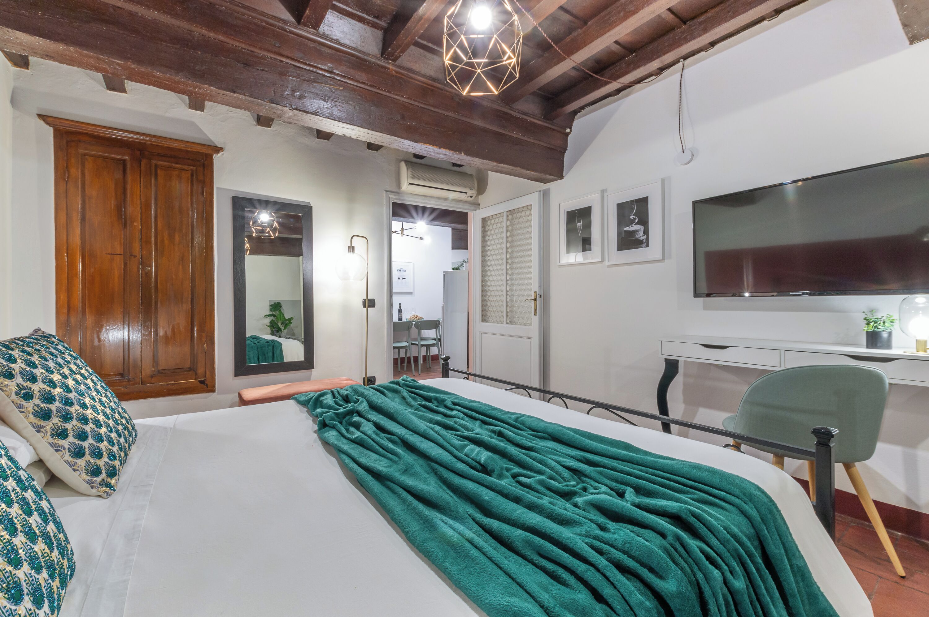 Une chambre à coucher avec un grand lit, un bureau, une chaise, une télévision et une armoire.