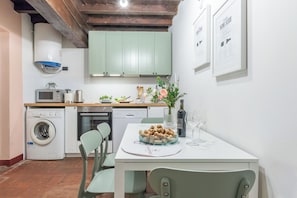 Una cucina dotata di lavatrice, forno a microonde e un tavolo con sedie.