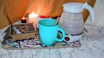 A table with a candle, a mug, a kettle, and a decorative box.