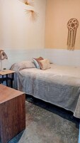 Quarto com cama, escrivaninha e um sonhador pendurado na parede.