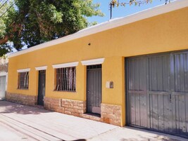 Um edifício amarelo com três janelas e uma porta de garagem.