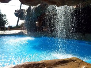 A pool with clear blue water and a rocky waterfall feature.