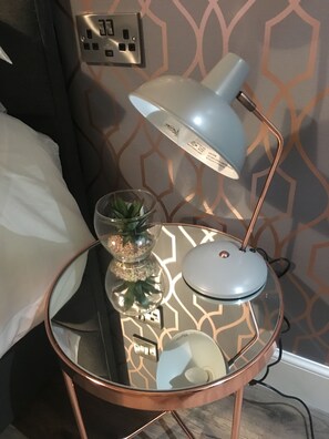 Cozy corner with a side table, desk lamp, and potted plant.