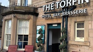 Die Torfin Hotel Bar & Brasserie mit traditioneller Steinauffassung, großen Fenstern und Außenbereich.