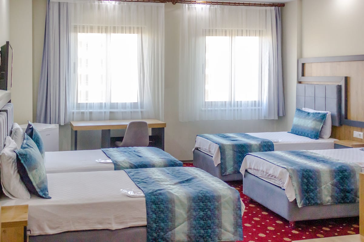 A hotel room with two single beds, a desk, a chair, and a small table.