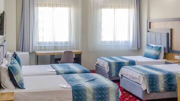 Una habitación de hotel con dos camas individuales, un escritorio, una silla y una mesita.