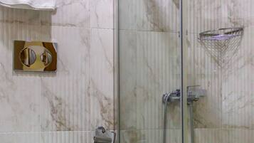 Ein Badezimmer mit einer Duschkabine, einer Toilette und einer Marmorwand.