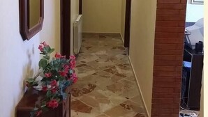 Un couloir doté d’un sol carrelé, de portes en bois et d’un mur en briques apparentes.