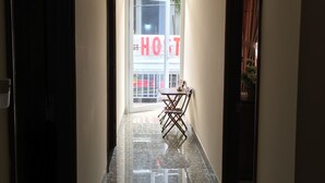 A hotel corridor with a polished marble floor, a dining area with a table and chairs, and a large window with a 'HOST' sign visible outside. - MaiLy Hostel (Hue)