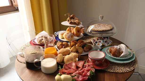 Un bufé de desayuno con diversos pasteles, panes, quesos y embutidos.