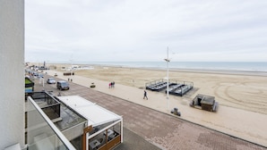 A beachside hotel with a view of the beach, outdoor seating, and a covered area. - Cortina 201 (Koksijde)