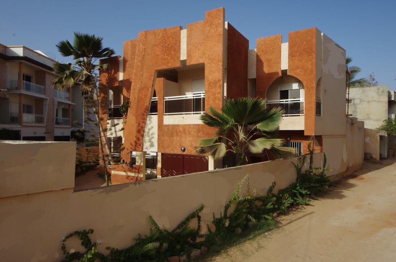 A modern building with a unique architectural design, featuring multiple balconies and a mix of brick and stucco materials.