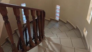 A spiral staircase with wooden railings and beige walls. - Villa Malaka (Dakar)