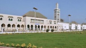 A large building with a central tower, surrounded by a green lawn and a row of arches. - Villa Malaka (Dakar)