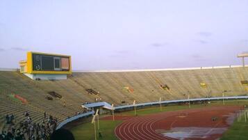 Un estadio con pista de atletismo, gradas para espectadores y marcador.