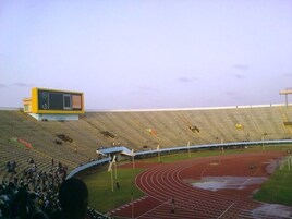 A stadium with a running track, spectator stands, and a scoreboard.