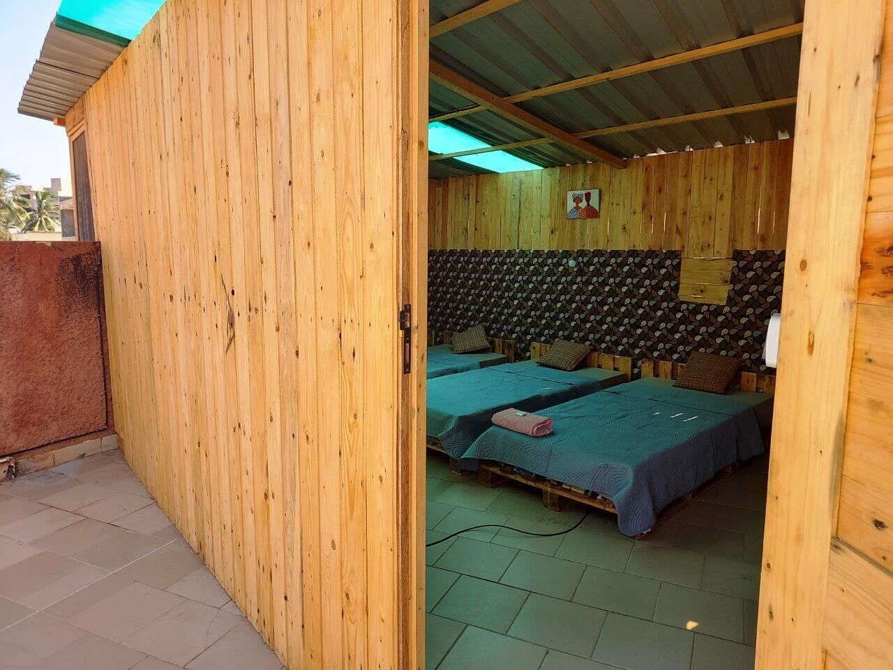 A wooden room with two beds, a small table, and a wall with a patterned design.