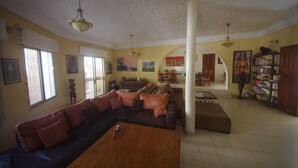 A spacious living room with a large sofa, a wooden coffee table, and a bookshelf. - Villa Malaka (Dakar)