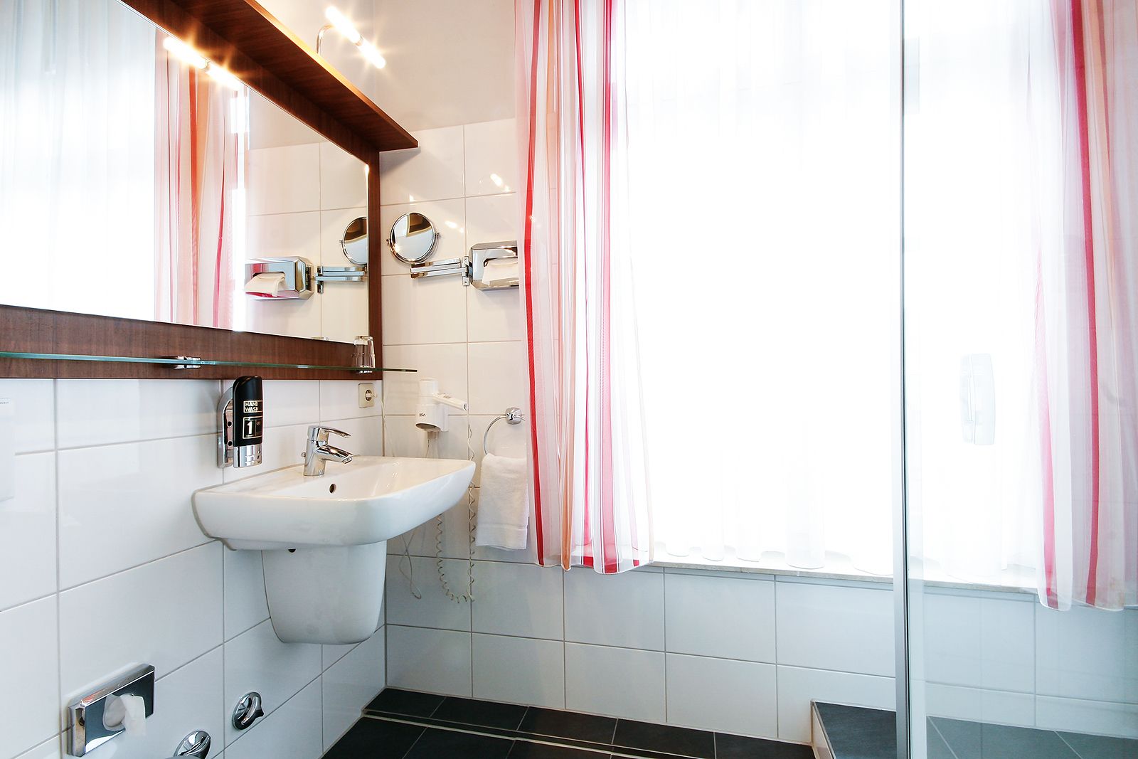 A bathroom with a white sink, a mirror, and a towel rack.