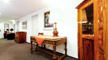 A room with a wooden desk, a lamp, a cabinet, and framed artwork on the wall.