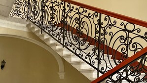 A staircase with ornate black metal railings and a wooden handrail.