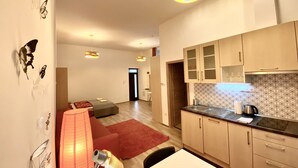 A modern kitchen with wooden cabinets, a sink, and a countertop. There is a red rug on the floor and a lamp on a table.
