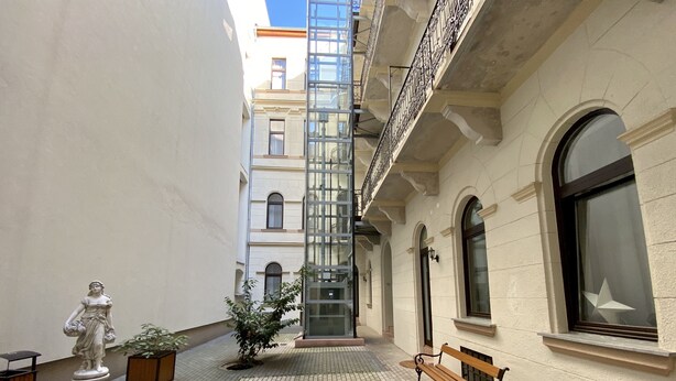 A courtyard with a statue, a bench, and potted plants.