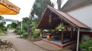 A rustic wooden building with a sloped roof and a covered outdoor seating area. - Pension Weidemühle (Kelbra)