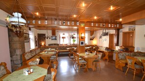 A restaurant with wooden furniture, multiple dining areas, and a stone wall. - Pension Weidemühle (Kelbra)