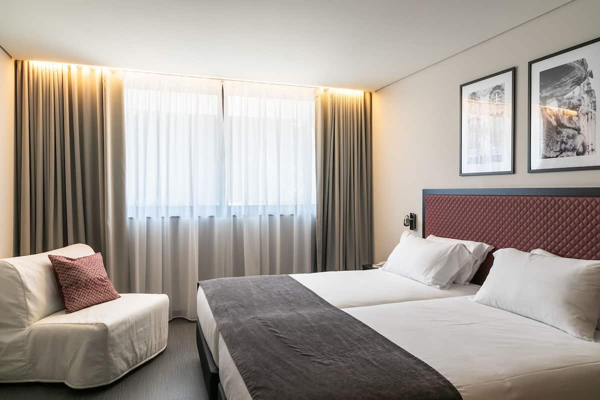 A hotel room with a bed, a sofa, and curtains.