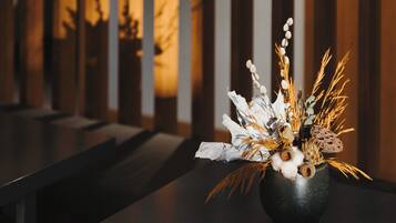 A dark wooden table with a black vase containing dried plants and branches.
