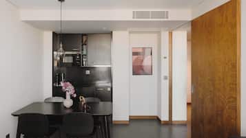 A modern kitchen with dark cabinetry, a dining table with chairs, and a vase with flowers.