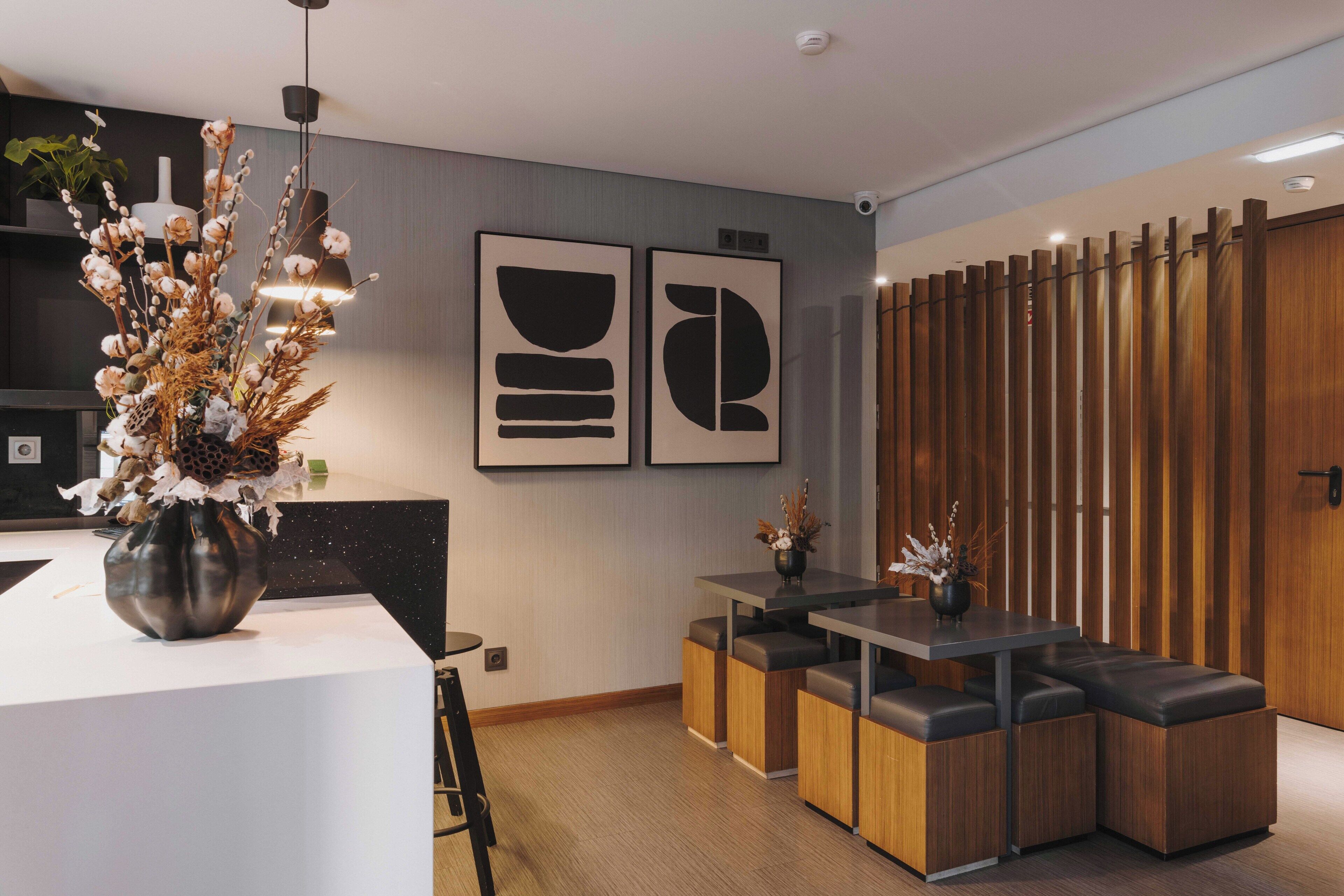 Een moderne keuken met een wit aanrecht, een vaas met gedroogde bloemen en een houten scheidingswand.