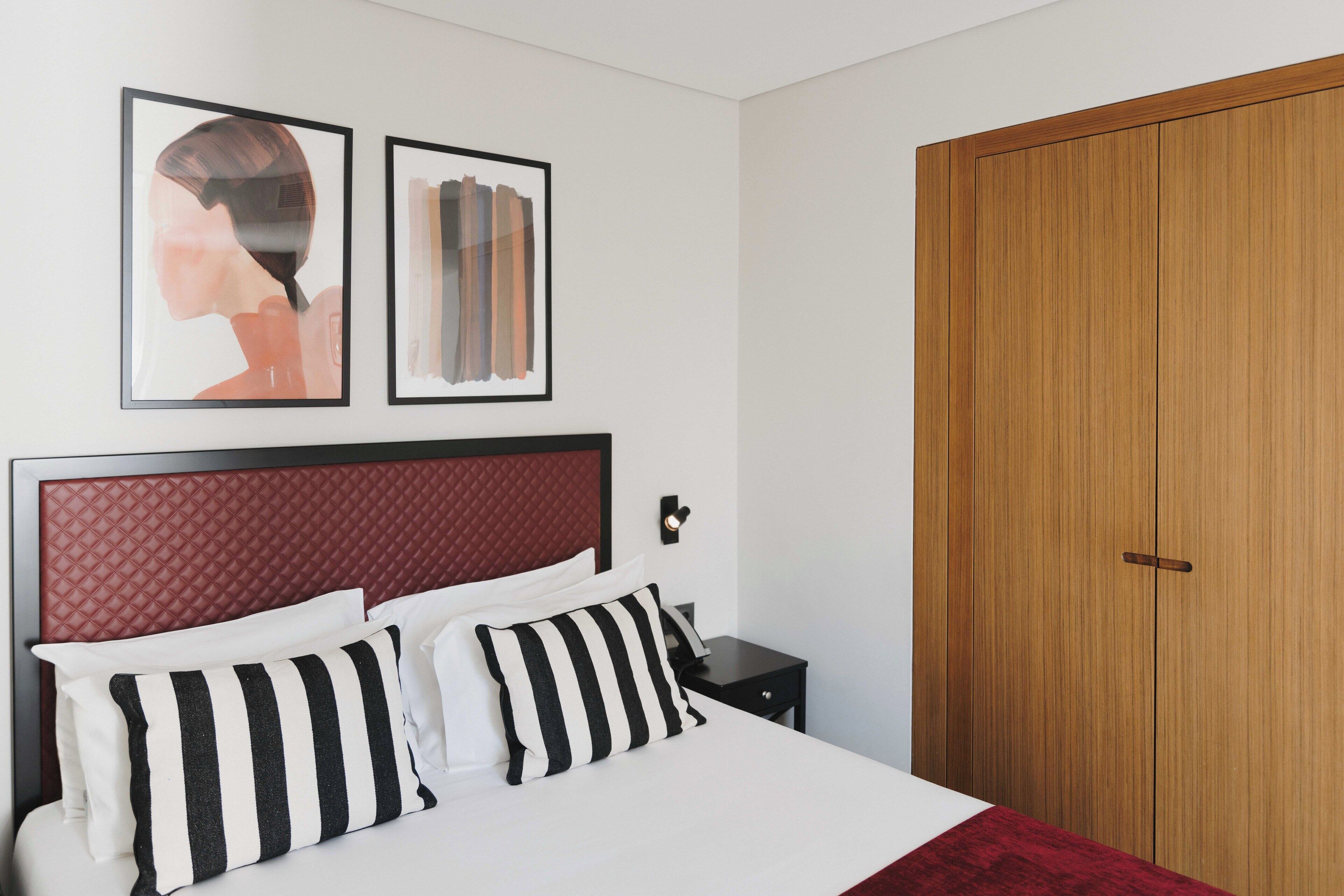 Een keurig opgeruimde hotelkamer met een bed, nachtkastje en een houten kledingkast.