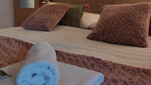 Un dormitorio con cabecera de madera, una toalla enrollada sobre la cama y un espejo en la puerta.