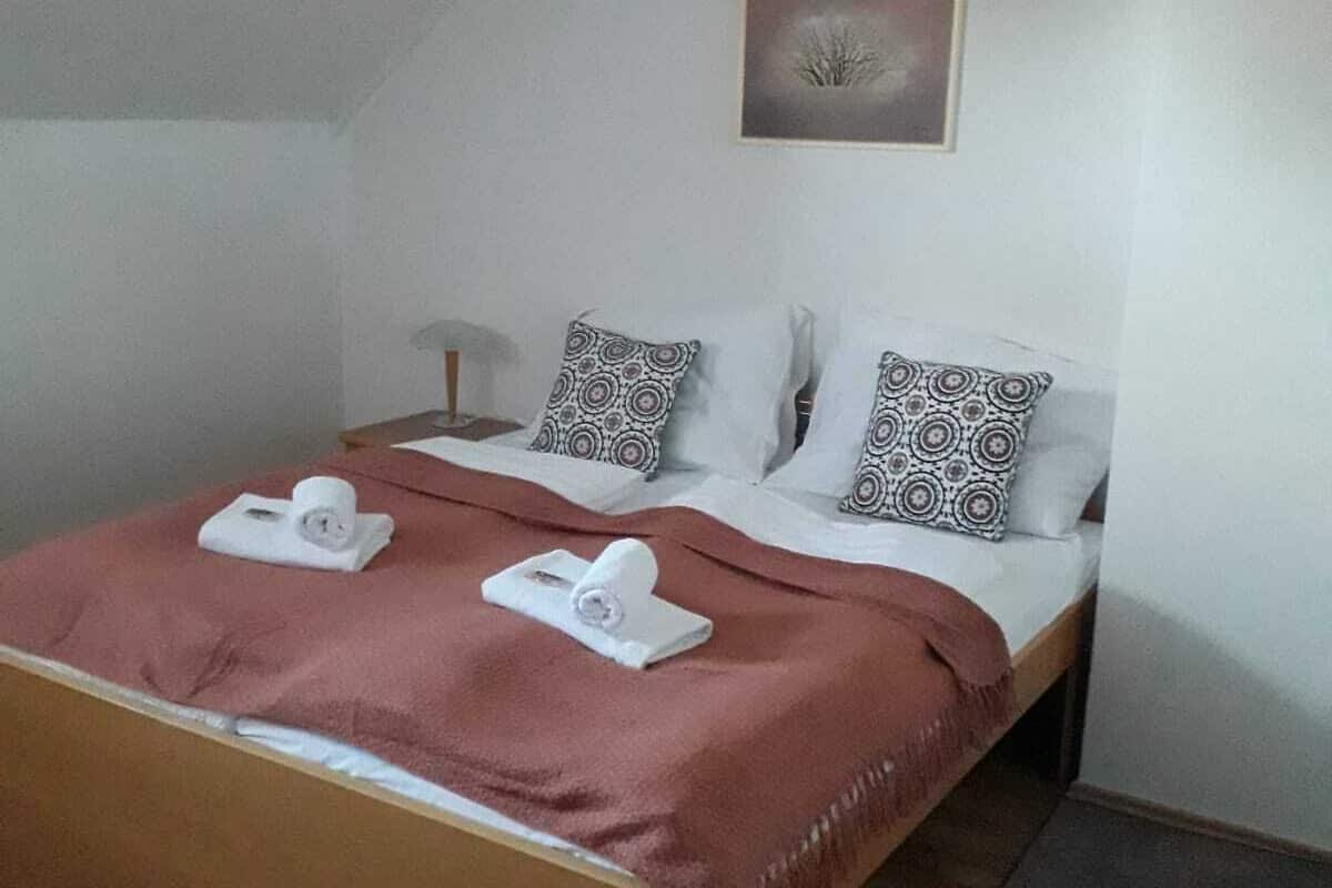 Une chambre à coucher avec un lit en bois, une couverture rose et des coussins à motifs.