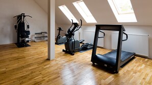 Un gimnasio con equipo de ejercicio, tragaluces y suelo de madera.