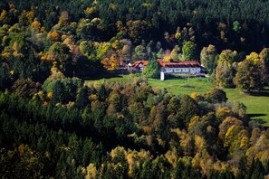 Ein weißes Gebäude mit rotem Dach, umgeben von dichtem Wald.