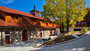 A courtyard with stone buildings, a wooden structure, and a tree with yellow leaves.