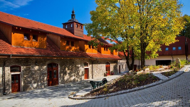 Un patio con edificios de piedra, una estructura de madera y un árbol con hojas amarillas.