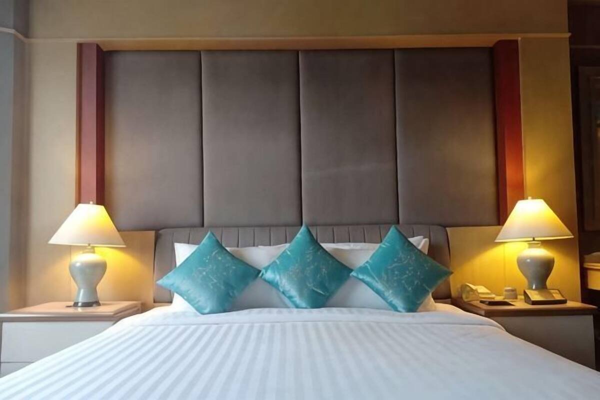 A hotel room with a large bed, two bedside tables with lamps, and a padded headboard.