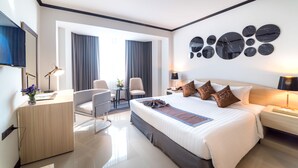 A modern hotel room with a large bed, a desk, a chair, and a TV.