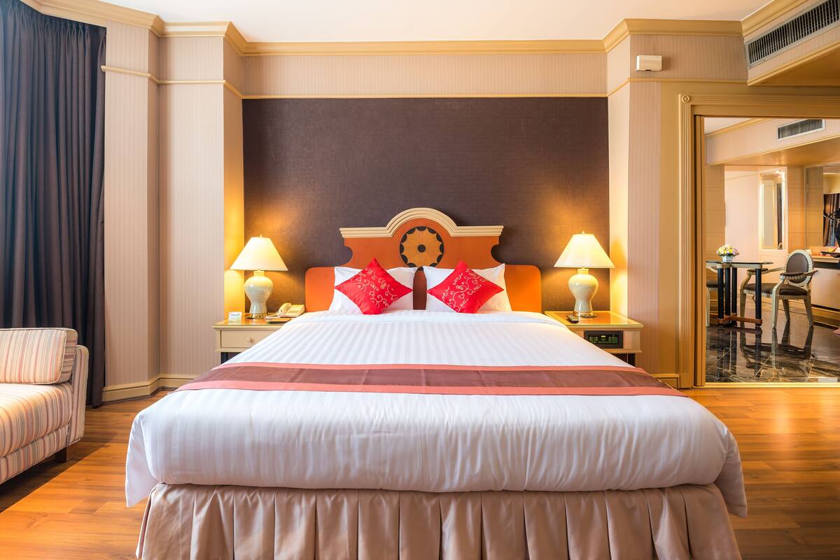 A hotel room with a large bed, two bedside lamps, a nightstand, a chair, and a mirror.