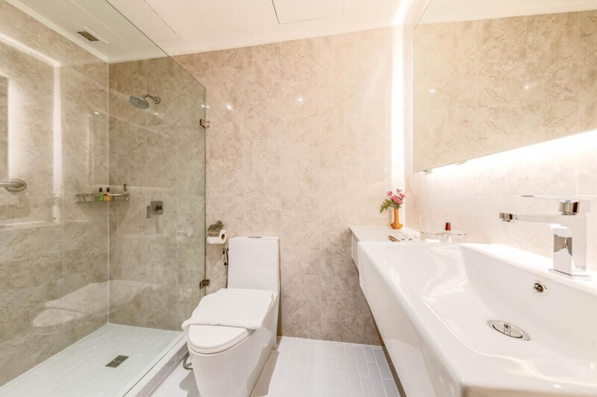 A modern bathroom with a glass-enclosed shower, a white toilet, and a large white bathtub.