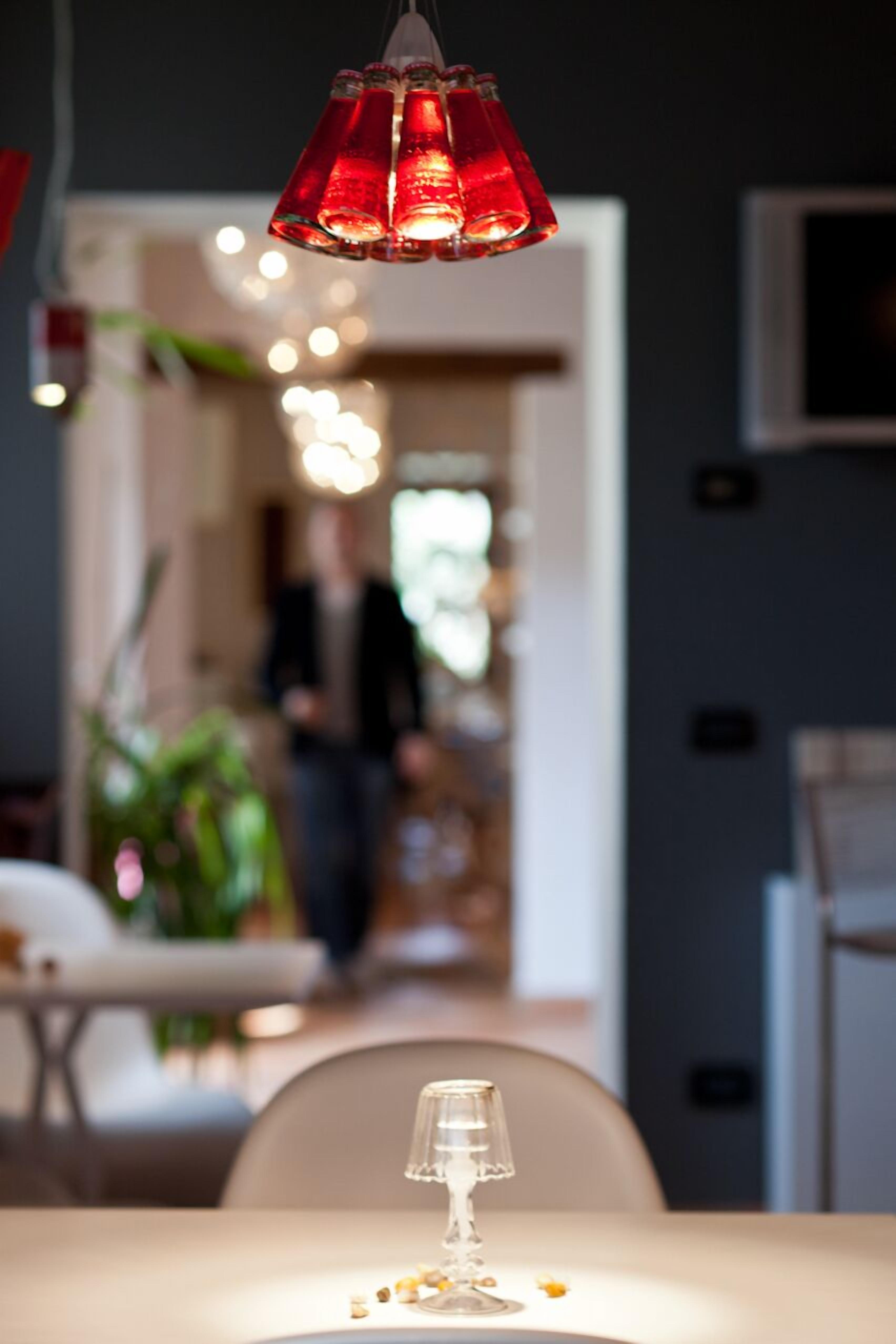 A dining area with a table set for two, a hanging red pendant light, and a blurred background suggesting a public space.