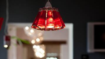 A dining area with a table set for two, a hanging red pendant light, and a blurred background suggesting a public space.